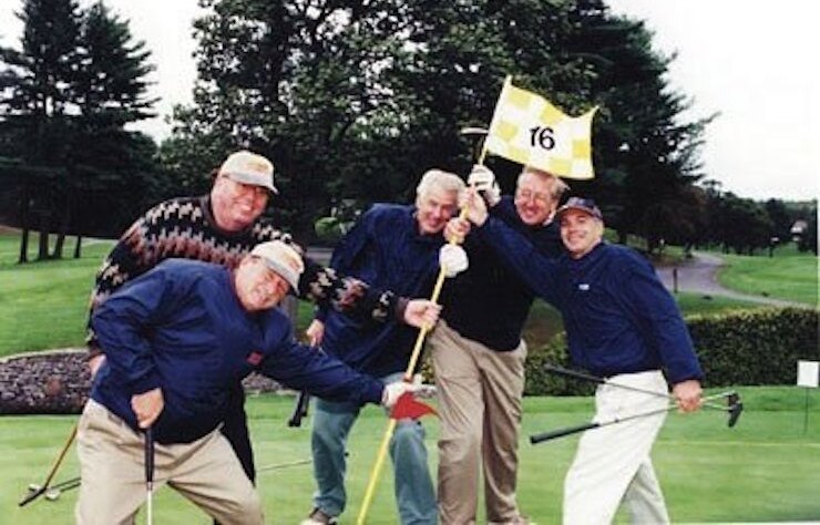 Jimmy Fund golfers on the green holding the number 16 flagstick
