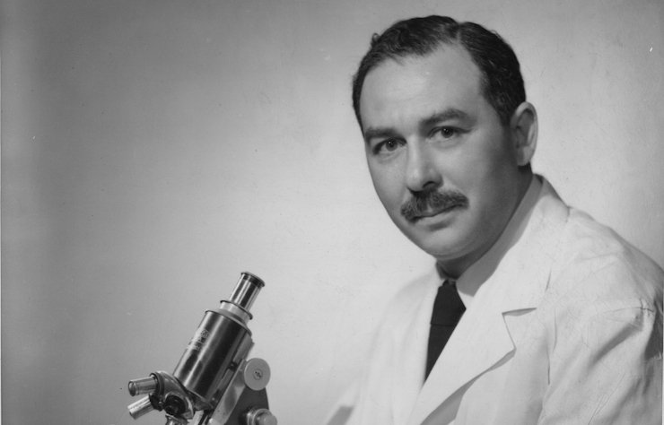 Black and white photo of Dr. Sidney Farber with a microscope