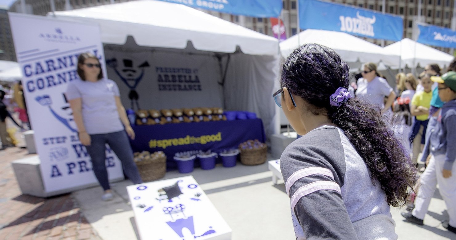 A Jimmy Fund Scooper Bowl attendee tossing a bean bag onto a cornhole board