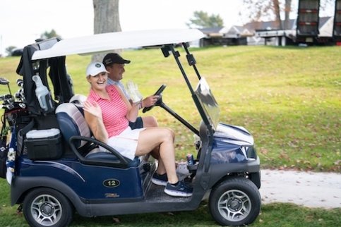 Two golfers in a golf cart on a course