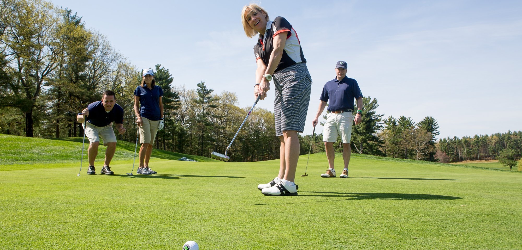 Four golfers playing a round on a course on a sunny day