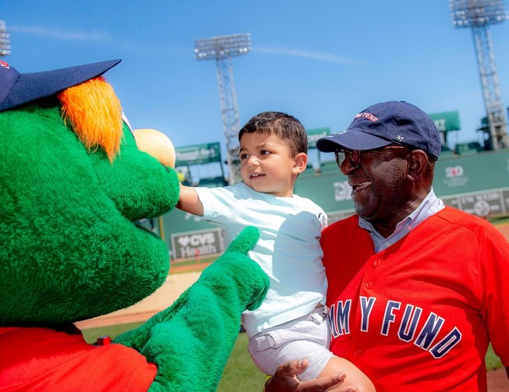 Two people interacting with Wally at Fenway Park