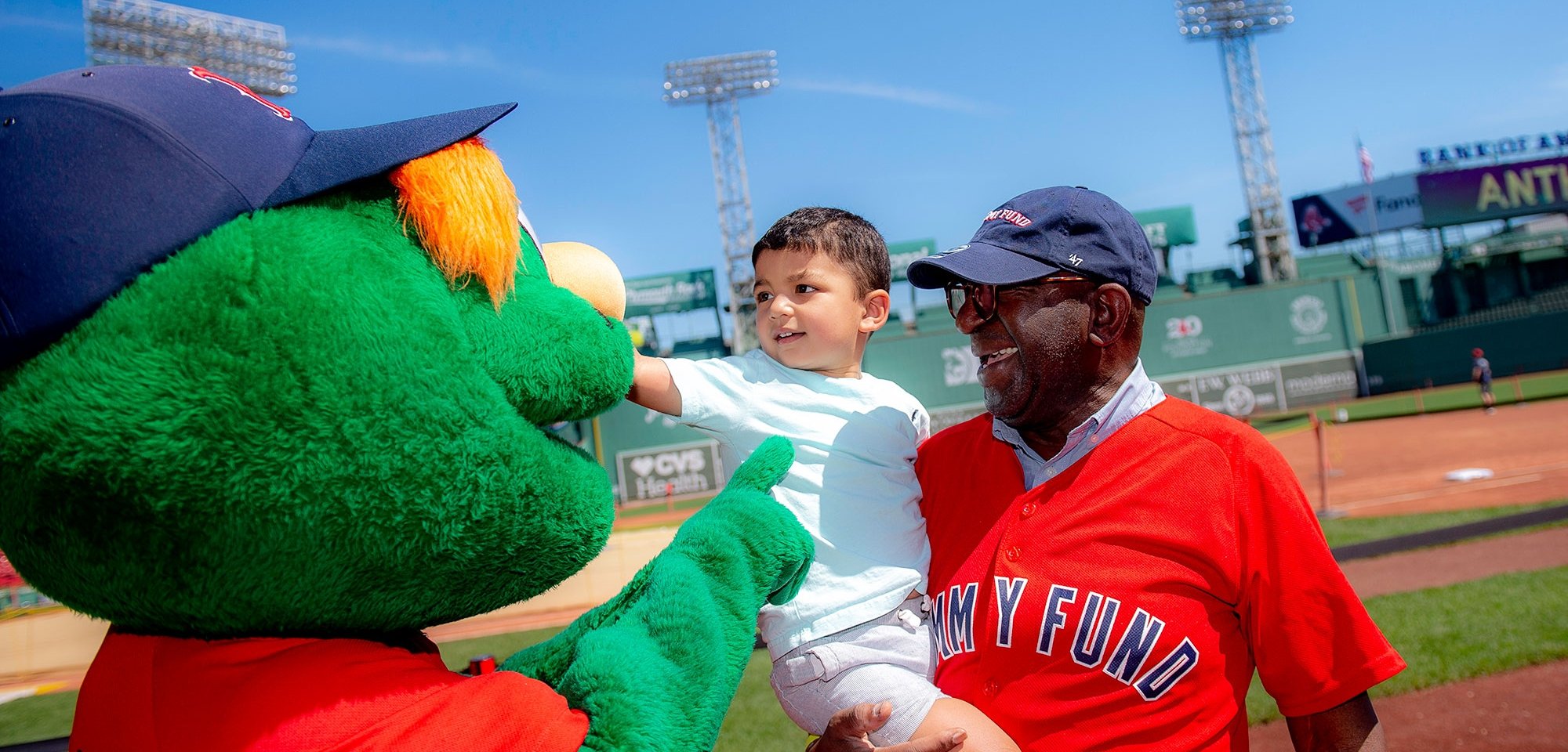 Two people interacting with Wally at Fenway Park