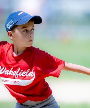 Little League player throwing a ball wearing Jimmy Fund gear