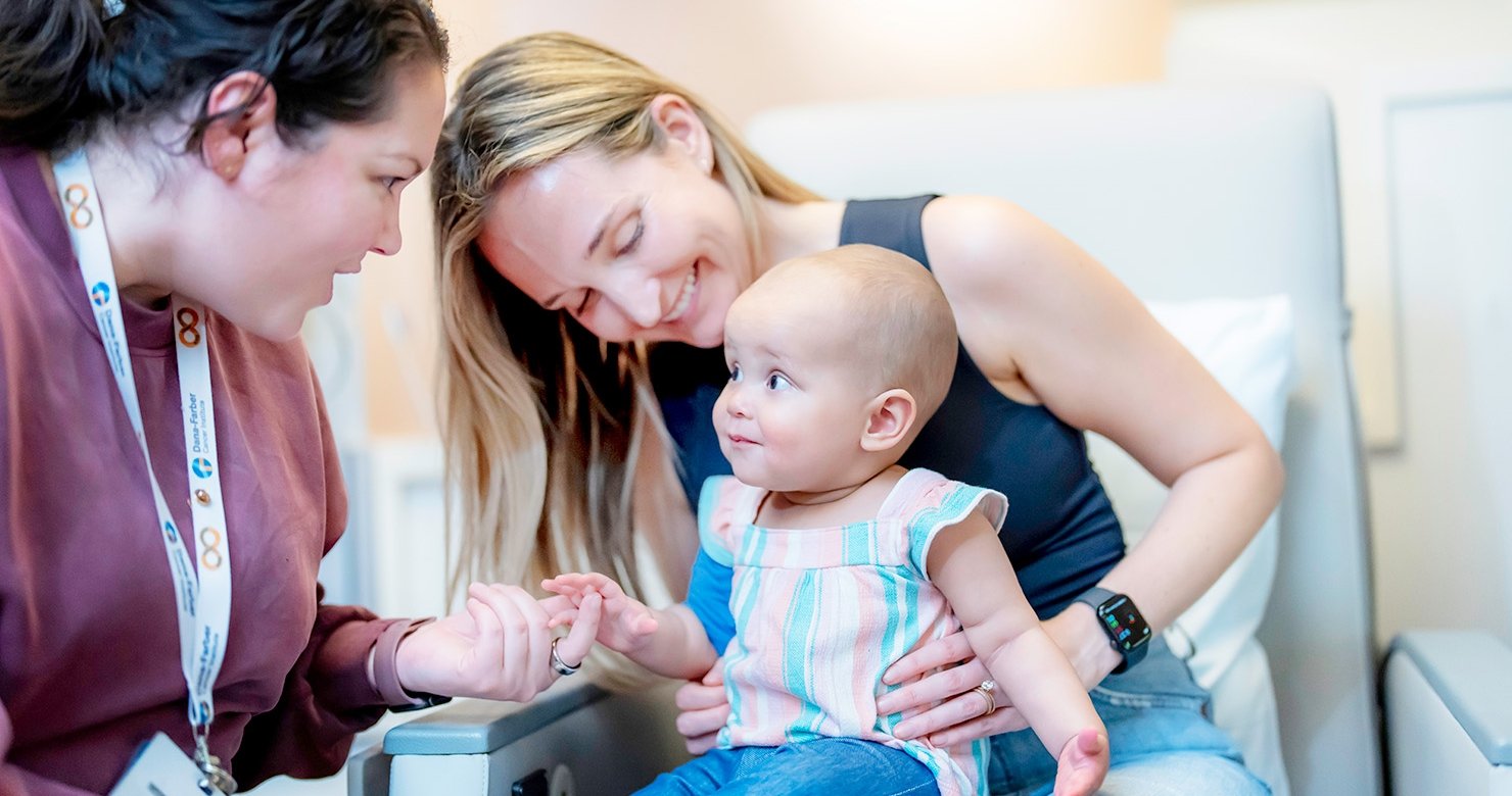 Leilani, a 1-year-old patient, smiling in a treatment chair with her clinical provider in Dana-Farber's Jimmy Fund Clinic