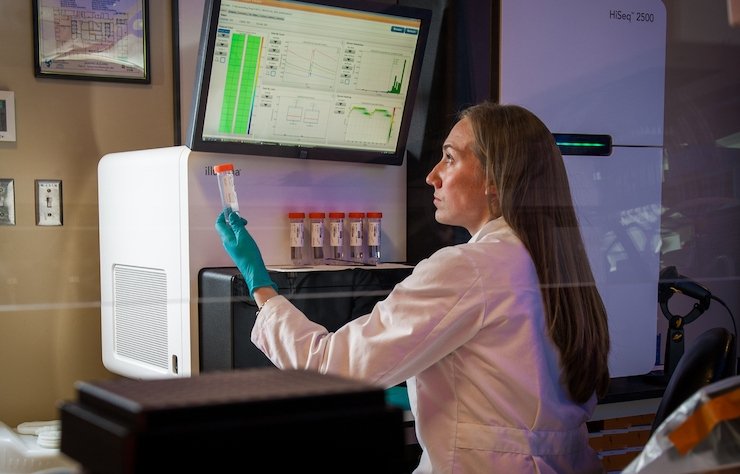A lab technician analyzing data at a sequencing machine