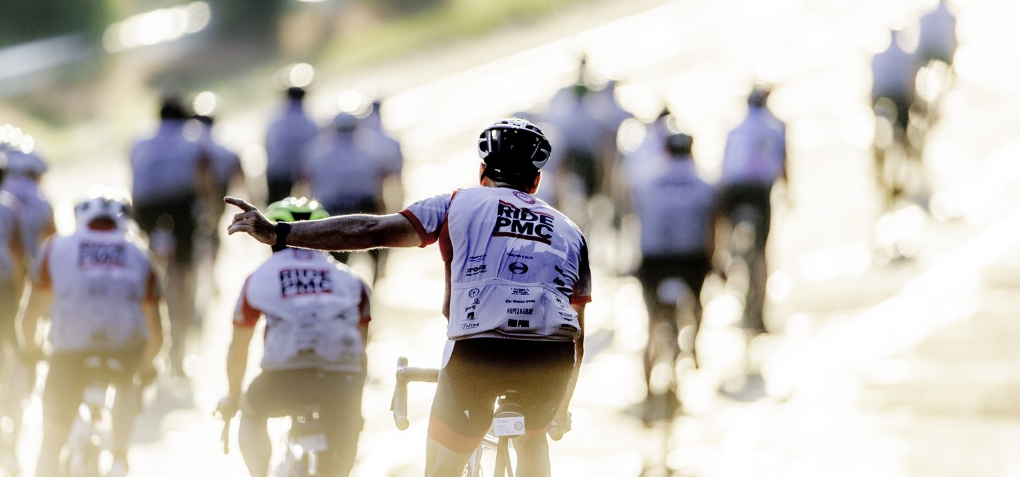 Group of bike riders with their backs to the camera wearing 'Ride PMC' jerseys
