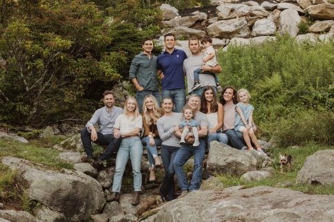 Stacey with her family, standing on a pile of boulders surrounded by trees