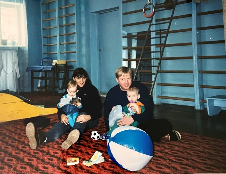Family sits on floor looking at books at orphanage in Ukraine