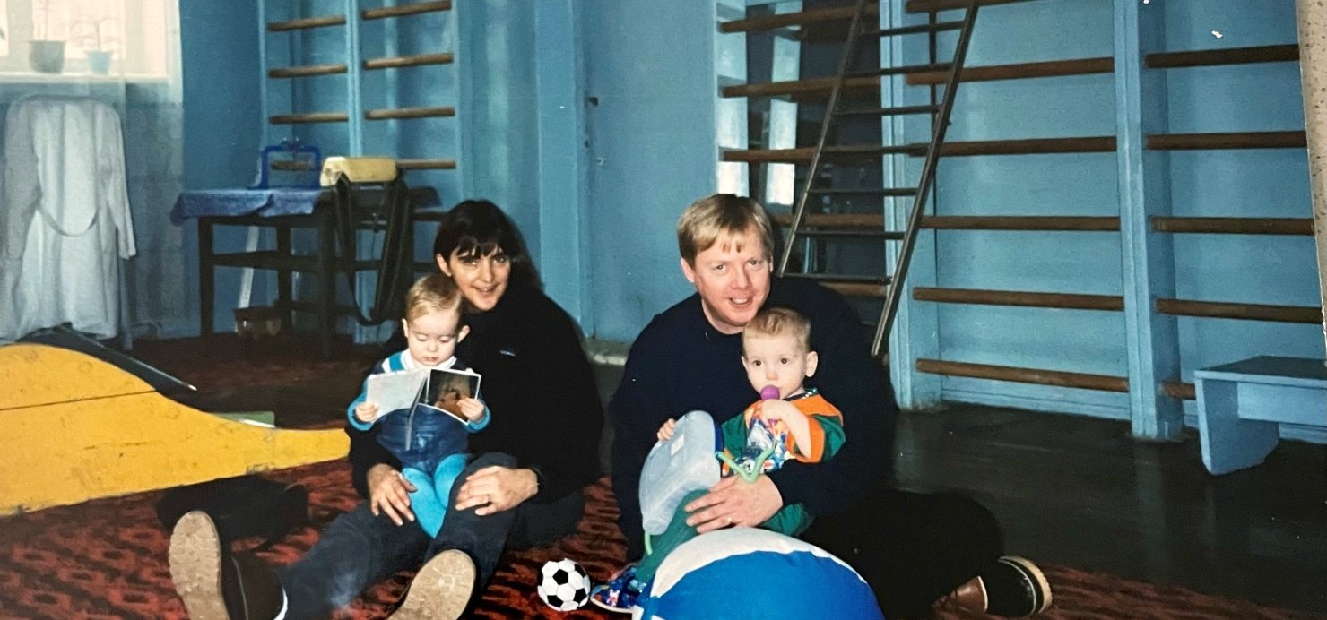 Family sits on floor looking at books at orphanage in Ukraine