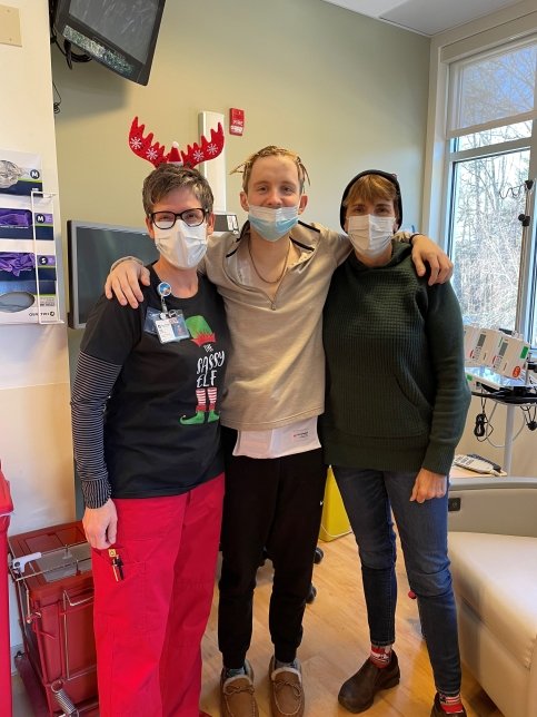 Corey stands with mother and nurse in a medical room