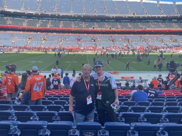 Corey and dad stand together with football field behind them