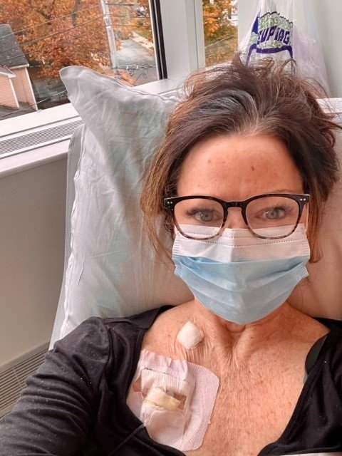 Deb in a hospital bed wearing a mask