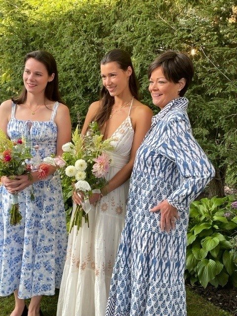 Deb stands with two daughters at a wedding