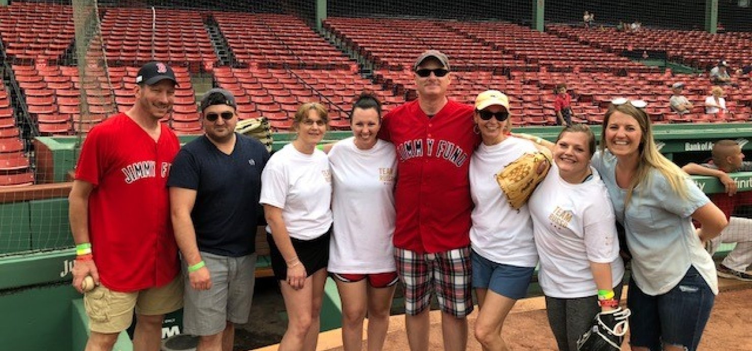 Andy standing in front of the bleachers at Fenway Park with family and friends