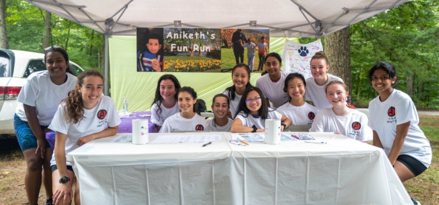 Family sitting in front of a ‘Aniketh’s Fun Run’ sign