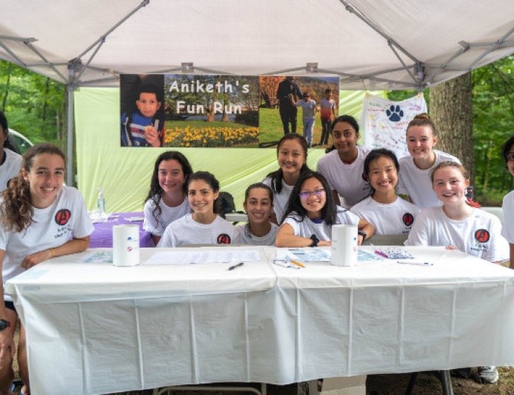 Family sitting in front of a ‘Aniketh’s Fun Run’ sign