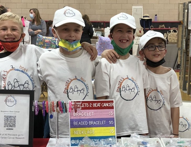 Four friends stand behind bracelet booth