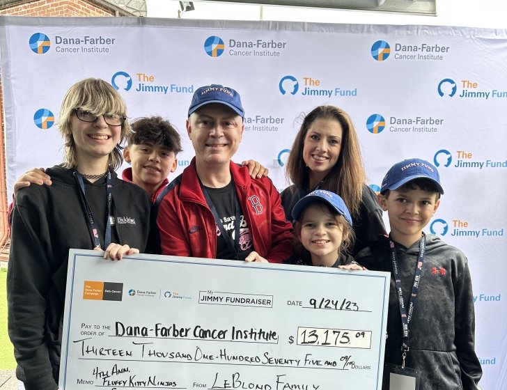 James and family hold a large check in front a Jimmy Fund backdrop