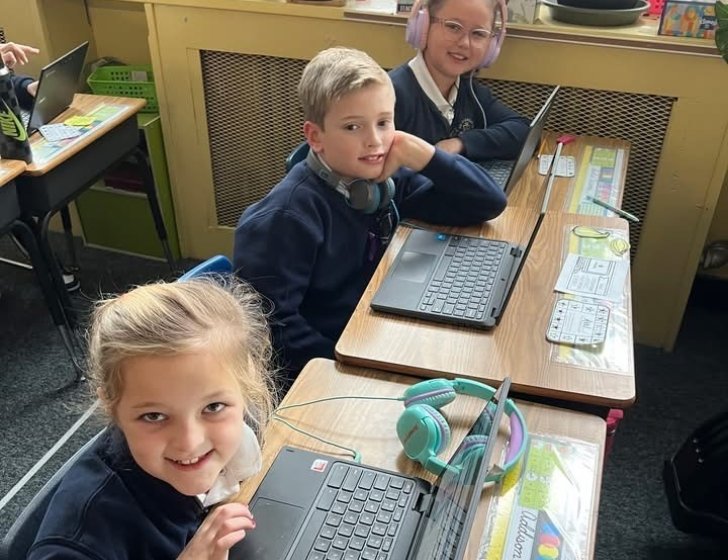 Three students at desks with laptops