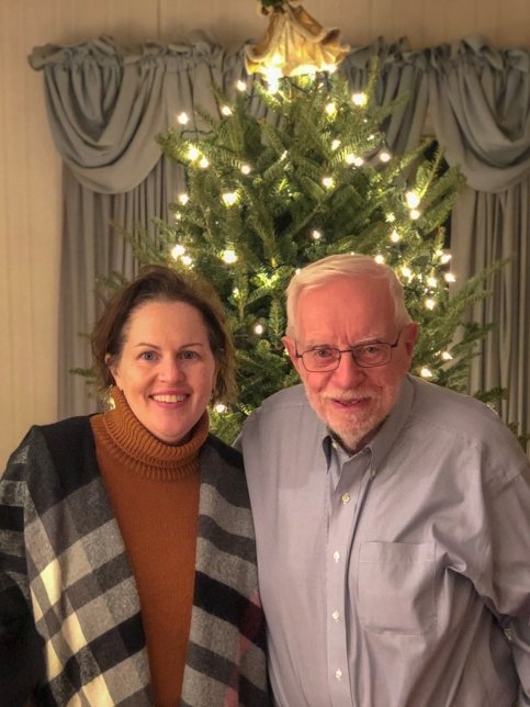 Katie and her dad in front of a Christmas tree