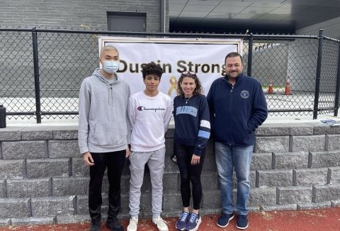 Dustin and Amine stand with two people in front of a “Dustin Strong 5k” sign