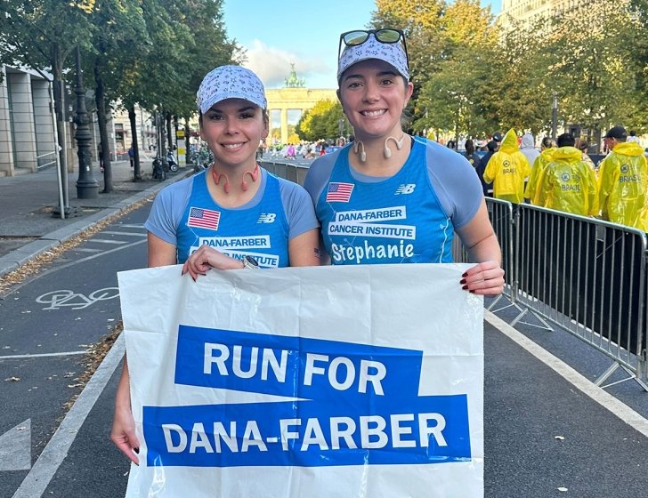 Kristina and Stephanie in their running gear holding a Run for Dana-Farber sign