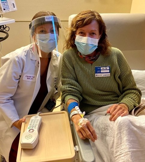 Patient and doctor sit in medical room wearing masks