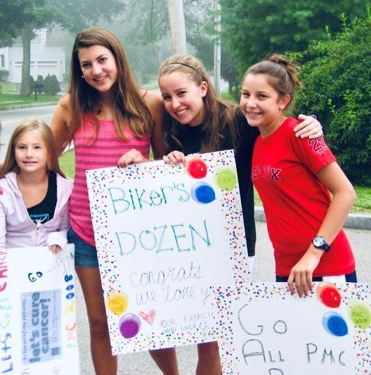 Sarah stands with group of kids holding inspirational signs