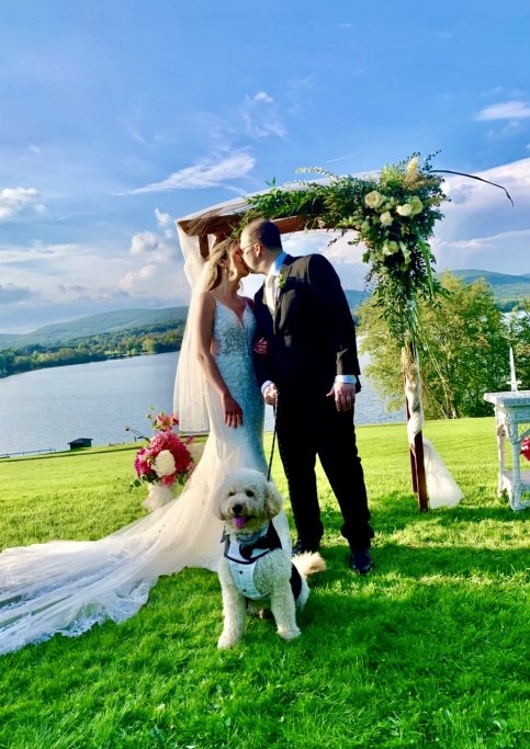 Matt and Aleah kiss on their wedding day with a lake and mountains in the background