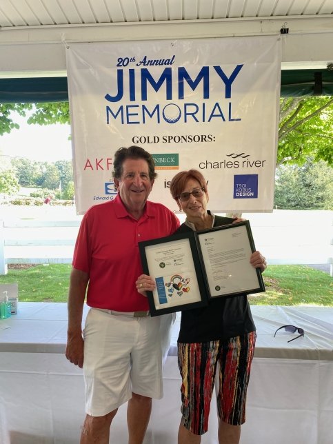 Two people stand in front of a '20th Annual Jimmy Memorial' sign