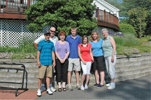 Family stands together in front of a garden