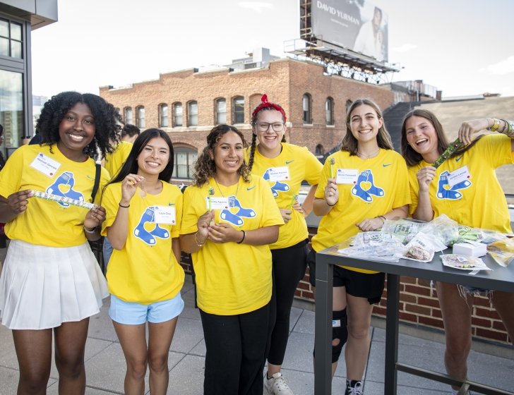 Group of scholars stand together on a roof deck wearing Red Sox T-shirts