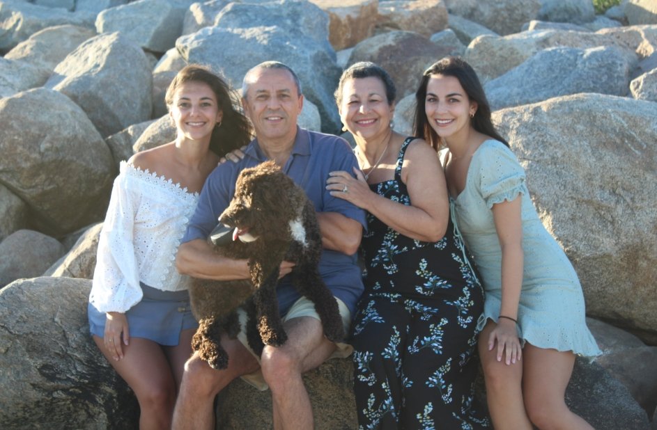 Family of four sit on rocks together, holding a dog