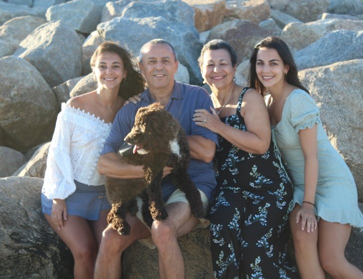Family of four sit on rocks together, holding a dog