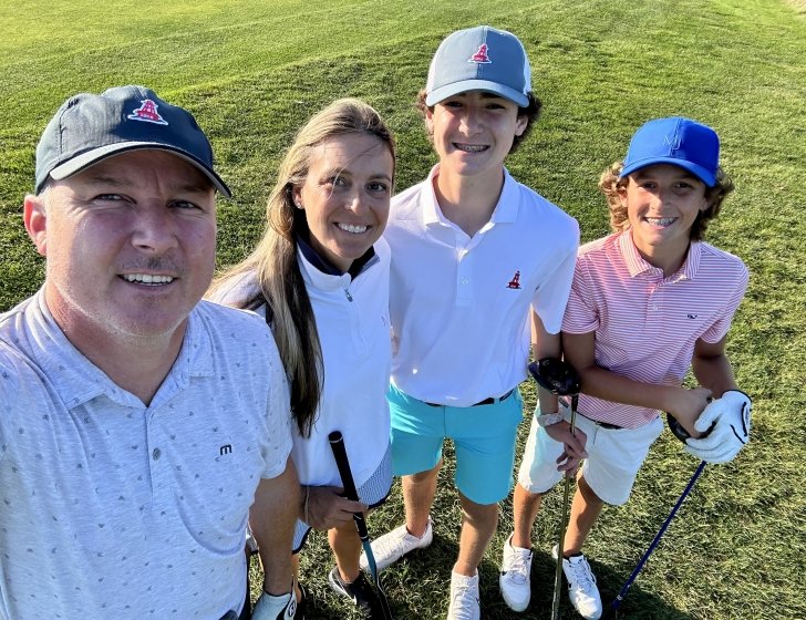 Julie and family stand together holding golf clubs