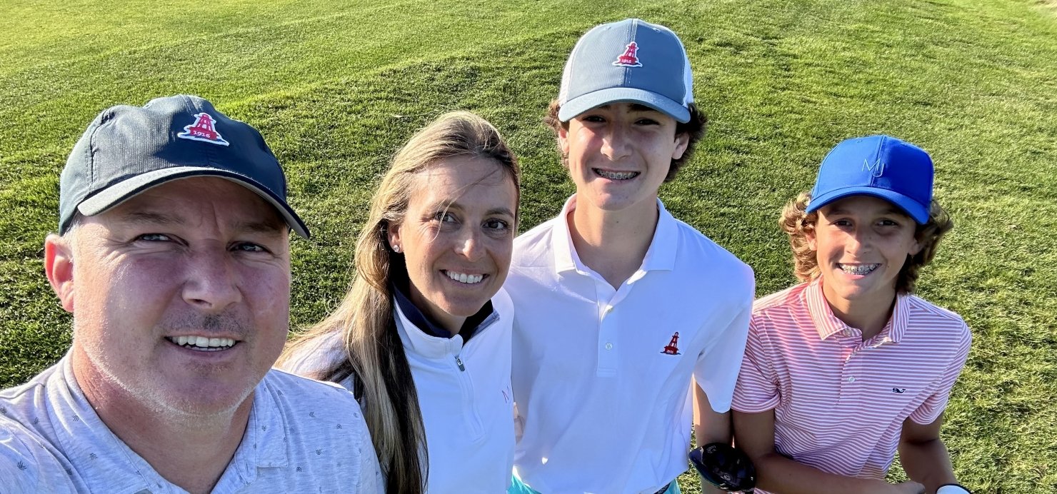 Julie and family stand together holding golf clubs