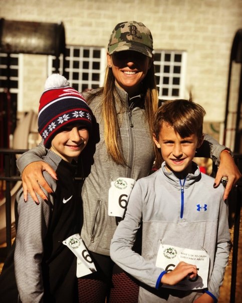 Julie hugs two children, all wearing workout clothes and 5K race bibs