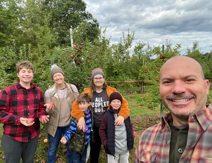 Family together stands in apple orchard