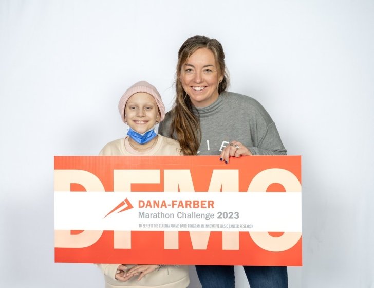 Sasha and Beth stand together holding a Dana-Farber Marathon Challenge 2023 sign