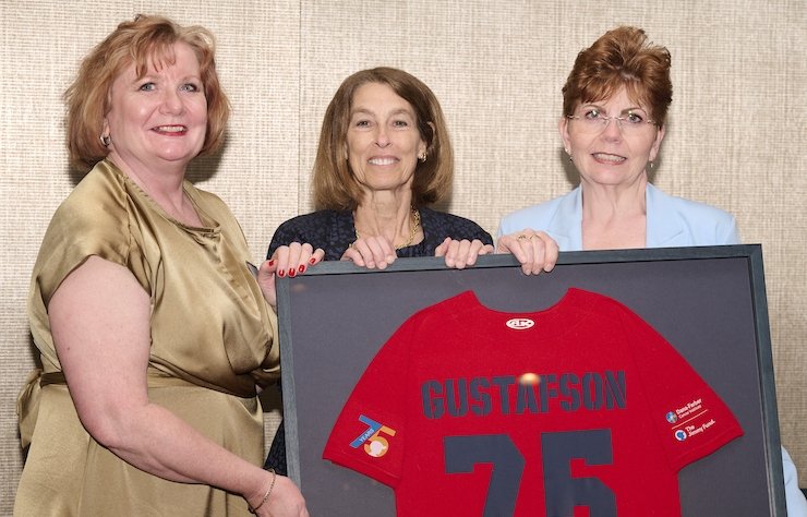 Einar’s daughters with then Dana-Farber President and CEO Laurie H. Glimcher, MD, holding a Gustafson jersey