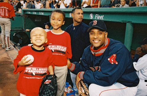 Red Sox player with two children in front of a dugout