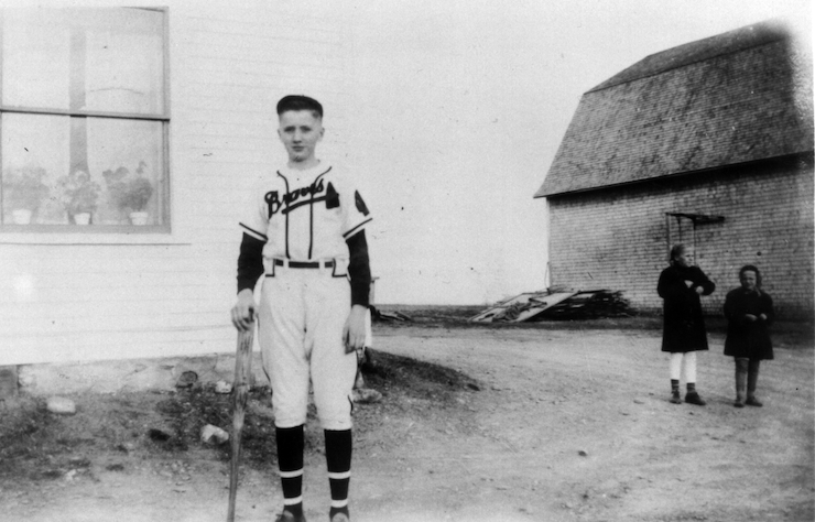 Black and white photo of Einar in a baseball uniform at home on his family farm in Maine