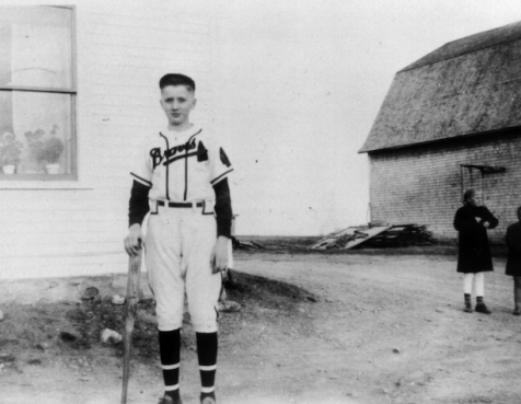 Black and white photo of Einar in a baseball uniform at home on his family farm in Maine