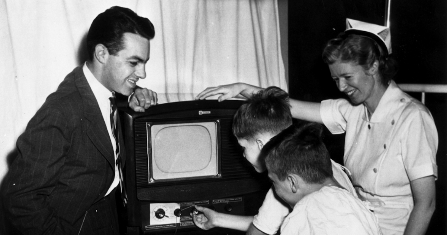 Black and white photo of adults and children watching TV