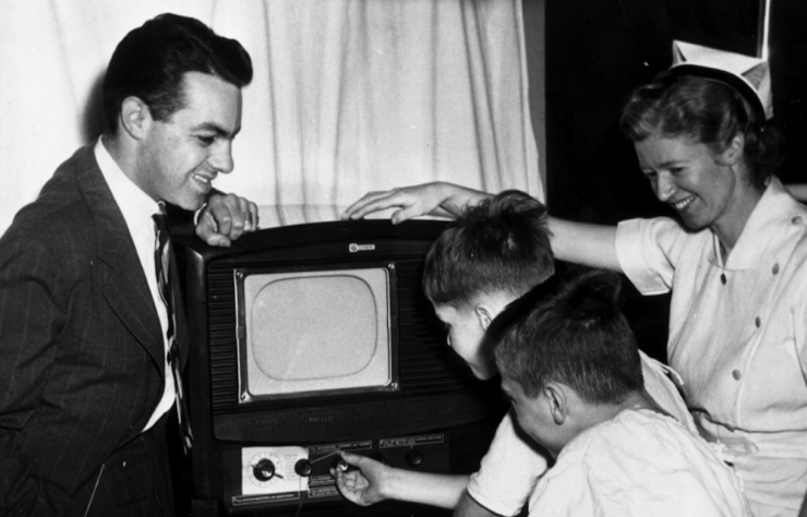 Black and white photo of adults and children watching TV